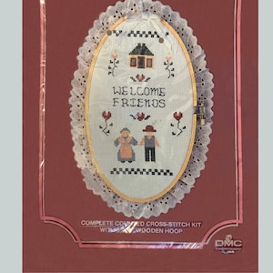Puede incluir: Un kit completo de punto de cruz contado con un aro de madera que incluye un lienzo ovalado blanco con un diseño de punto de cruz de una casa, dos figuras y el texto "WELCOME FRIENDS".