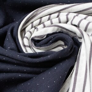 May include: Close-up of two fabric swatches. One is a dark blue fabric with white polka dots. The other is a white fabric with gray stripes.