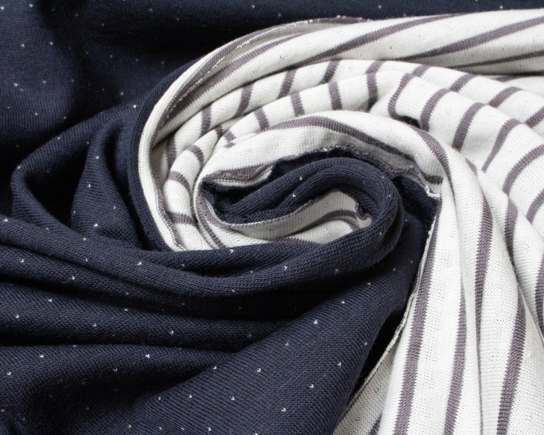 May include: Close-up of two fabric swatches. One is a dark blue fabric with white polka dots. The other is a white fabric with gray stripes.