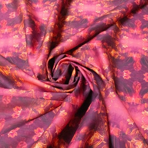 May include: A close-up of a pink and orange fabric with a floral pattern. The fabric is folded and draped, creating a soft and flowing texture.