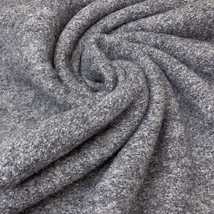 May include: A close-up of a soft, grey fabric with a slightly textured surface. The fabric is folded and draped, creating a swirling pattern.