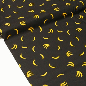 May include: Black fabric with a repeating pattern of yellow bananas. The fabric is folded and a label with the text "RUBY STAR SOC" is visible.
