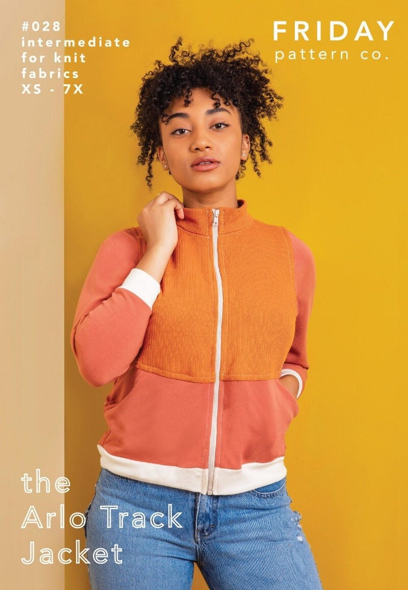 Puede incluir: Una mujer lleva una chaqueta con cremallera de dos tonos, naranja y coral, con ribete blanco. La chaqueta se llama "the Arlo Track Jacket" y es de "FRIDAY pattern co.". Tambi&eacute;n se puede ver el texto "#028 intermediate for knit fabrics XS-7X".