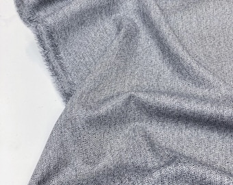 May include: Close-up of a gray textured fabric with a subtle sheen. The fabric is folded and draped, showcasing its soft and drapey texture.