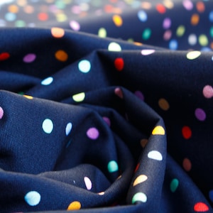 May include: A dark blue fabric with a colourful polka dot pattern. The fabric is folded and draped, showing the texture and pattern.