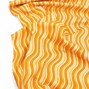 以下が含まれることがあります： オレンジと白のストライプの生地で、波打つようなパターンになっています。生地は折り畳んでドレープされています。