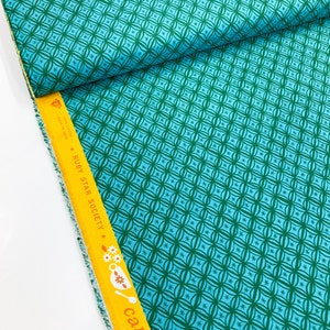 May include: Teal fabric with a repeating pattern of green circles and stars. The fabric has a yellow label with the text "* RUBY STAR SOCIETY *" and "camellia" printed on it.