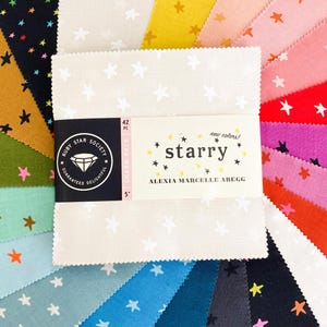 May include: A selection of colourful fabric squares with a star design. The central pack is labelled "starry" with the text "new colours!" and "ALEXIA MARCELLE ABEGG". Each square measures 12.7 cm.