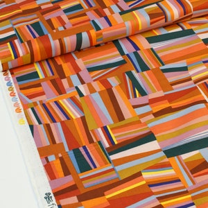 May include: Abstract geometric fabric with a patchwork design featuring orange, brown, blue, pink, and green stripes. The fabric is made of cotton and is perfect for quilting, sewing, and crafting.