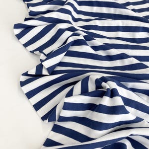 May include: White and navy blue striped fabric. The fabric is soft and stretchy, perfect for sewing projects.