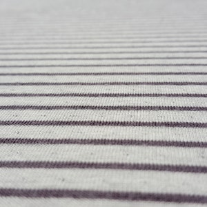 May include: Close-up of a white and gray striped fabric with a subtle texture.