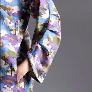 May include: A long-sleeved dress with a blue background and a colourful floral print. The dress has a ruffled cuff on the sleeve.