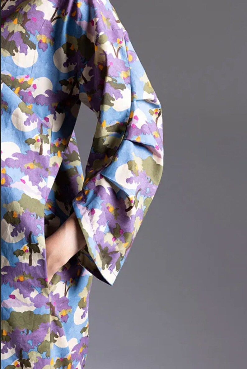 May include: A long-sleeved dress with a blue background and a colourful floral print. The dress has a ruffled cuff on the sleeve.