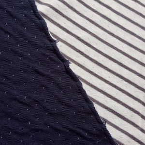 May include: Close-up of two different fabrics sewn together. One side is a dark blue fabric with a subtle dotted pattern. The other side is a white fabric with thin, gray stripes.