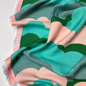 May include: A fabric with a repeating pattern of pink, teal, and green clouds. The fabric is folded and the edges are frayed. The text "Elixir" and "Melody Miller" are visible on the fabric.