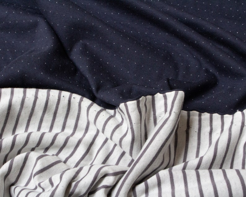 May include: A fabric with a navy blue polka dot pattern on the top half and a white and gray striped pattern on the bottom half.
