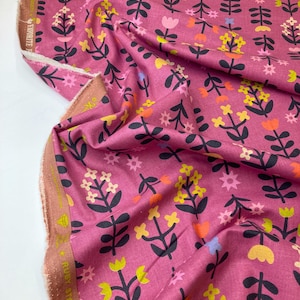 Könnte beinhalten: Rosafarbener Stoff mit einem Blumendruck mit schwarzen Stielen, gelben und orangen Blumen sowie rosa und weißen Blumen. Der Stoff hat einen weißen Rand mit dem Text "RUBY STAR SOCIETY" und "FAVORITE FABRIC" in Gold.