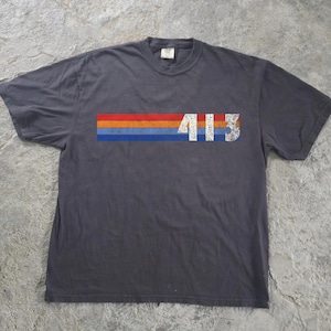 May include: A charcoal gray short-sleeve t-shirt featuring a horizontal graphic across the chest. The graphic consists of three stacked stripes in red, orange, and blue, with the white distressed-style numbers 413 printed over the stripes.