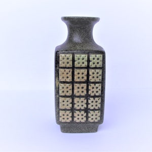 Peut inclure: Un vase en céramique vert foncé avec un corps carré et un col étroit. Le vase présente un motif géométrique de carrés avec un design texturé en relief dans une nuance de vert plus claire.