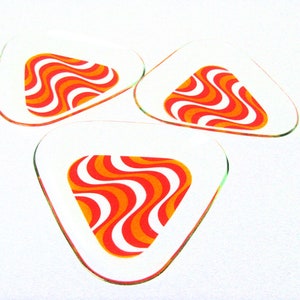 Peut inclure: Trois sous-verres triangulaires en verre transparent avec un motif ondulé orange et blanc.