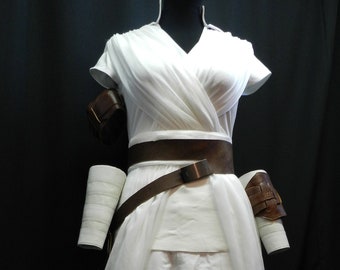May include: White costume with a brown belt and leather accents. The costume has a flowing skirt and pants with pockets.