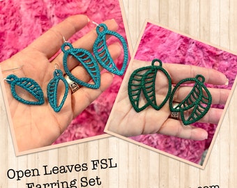 Könnte beinhalten: Zwei Paare offener Blatt-Ohrringe, ein Paar ist türkis und das andere dunkelgrün. Die Ohrringe sind aus Stoff und haben ein zartes, filigranes Design. Die Ohrringe werden auf einer Hand vor einem rosa flauschigen Hintergrund gezeigt. Der Text "Open Leaves FSL Earring Set www.designsbybabymoon.com" befindet sich am unteren Rand des Bildes.