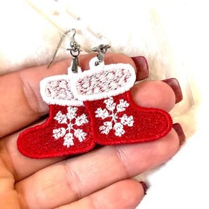 May include: Red and white Christmas stocking earrings with snowflake embroidery. The earrings are made of felt and have silver hooks.