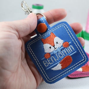 May include: Blue leather keychain with a fox design and the name "Benjamin" embroidered on it.
