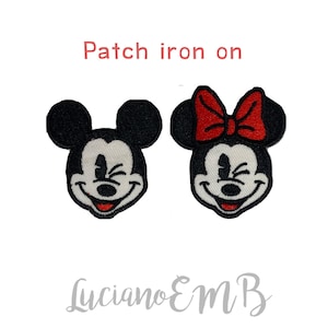 May include: Iron-on patch featuring Mickey Mouse and Minnie Mouse with a red bow. The characters are smiling and winking.