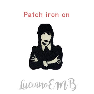 Puede incluir: Parche termoadhesivo en blanco y negro de una mujer con los brazos cruzados. El parche dice "Patch iron on" en la parte superior y "Luciano EMB" en la parte inferior.