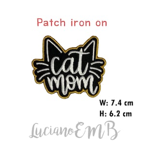 May include: Iron-on patch with a black cat silhouette and white text that reads "cat mom". The patch has a gold outline and measures 7.4 cm wide and 6.2 cm high.