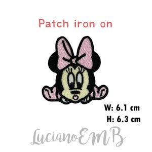 Può includere: Toppa da stirare con un personaggio dei cartoni animati con un fiocco rosa, orecchie nere e viso giallo. La toppa è larga 6,1 cm e alta 6,3 cm. "Patch iron on" è scritto sopra il personaggio. "Luciano EMB" è scritto sotto il personaggio.