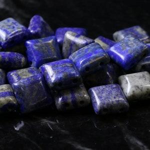 May include: A pile of square lapis lazuli beads with a dark blue and white marbled pattern.