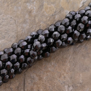 May include: A strand of black faceted hematite beads. The beads are round and have a shiny finish.