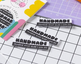 Könnte beinhalten: Drei weiße Stoff-Etiketten mit schwarzem Text, der "HANDMADE" und "IMAGINE WHAT ELSE I CAN DO" lautet.