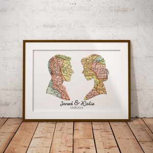 May include: A framed print with a vintage map design featuring two silhouettes of people. The text "Jared & Katie 10.08.2016" is printed below the silhouettes.