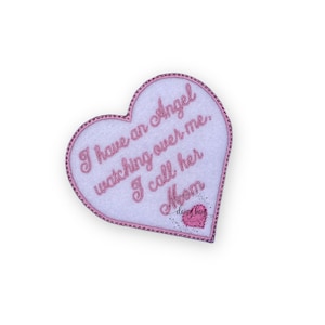 May include: Pink heart-shaped felt patch with white stitching and the text "I have an Angel watching over me. I call her Mom" in pink embroidery. The text "daisy bay" is also embroidered in pink with a small pink heart.
