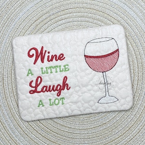 May include: A white quilted coaster with red embroidery that reads "Wine a little Laugh a lot" and a red wine glass illustration.
