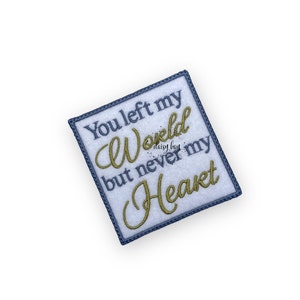 Puede incluir: Un parche cuadrado blanco con un borde azul y bordado dorado. El texto dice "You left my world but never my heart".