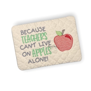 May include: Embroidered design on a beige fabric background with a red apple and the text "Because teachers can't live on apples alone!"