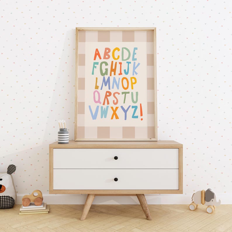 Puede incluir: Una l&aacute;mina de arte mural enmarcada que muestra el alfabeto con letras coloridas dibujadas a mano sobre un fondo de cuadros beige y blanco. Las letras est&aacute;n dispuestas en filas e incluyen todo el alfabeto de la A a la Z con un signo de exclamaci&oacute;n.