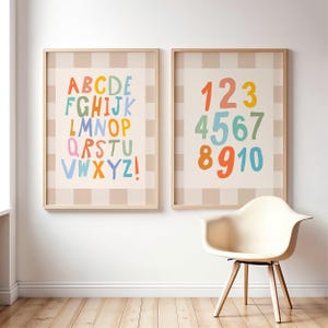May include: Two framed wall art prints featuring a light beige and white checkered border. The left print displays the alphabet in colorful, hand-drawn style letters from A to Z. The right print displays the numbers 1 through 10 in matching colors.