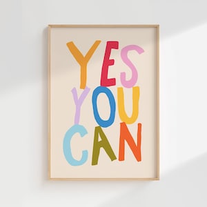 May include: A framed wall art print featuring the text YES YOU CAN in hand-drawn, multi-colored block letters. The letters are orange, red, pink, light purple, blue, yellow, light blue, olive green, and orange, set against a light beige background.