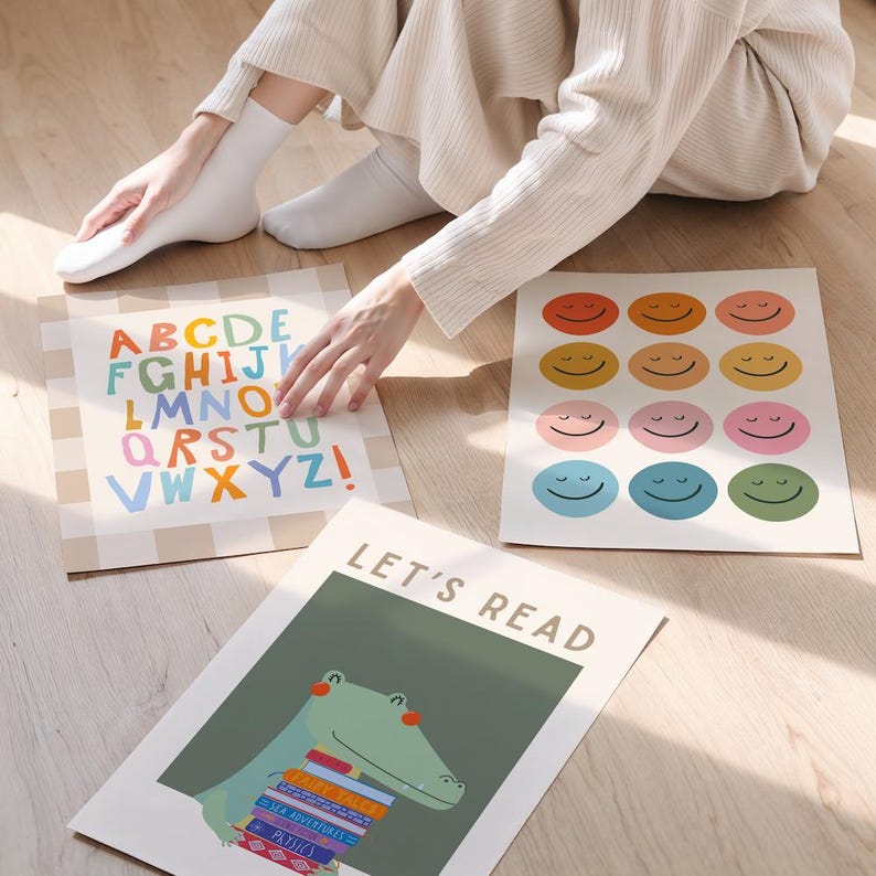 Puede incluir: Tres l&aacute;minas decorativas rectangulares con temas educativos. Una l&aacute;mina muestra el alfabeto en letras coloridas sobre un fondo de cuadros beige. Otra muestra doce caras sonrientes de varios colores. La tercera presenta un cocodrilo verde sosteniendo una pila de libros con el texto LET'S READ.