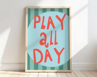 Puede incluir: Un póster enmarcado con las palabras "PLAY ALL DAY" en rojo. El texto está centrado en un círculo azul claro, sobre un fondo de rayas verticales verdes y azules. El marco es de madera clara.