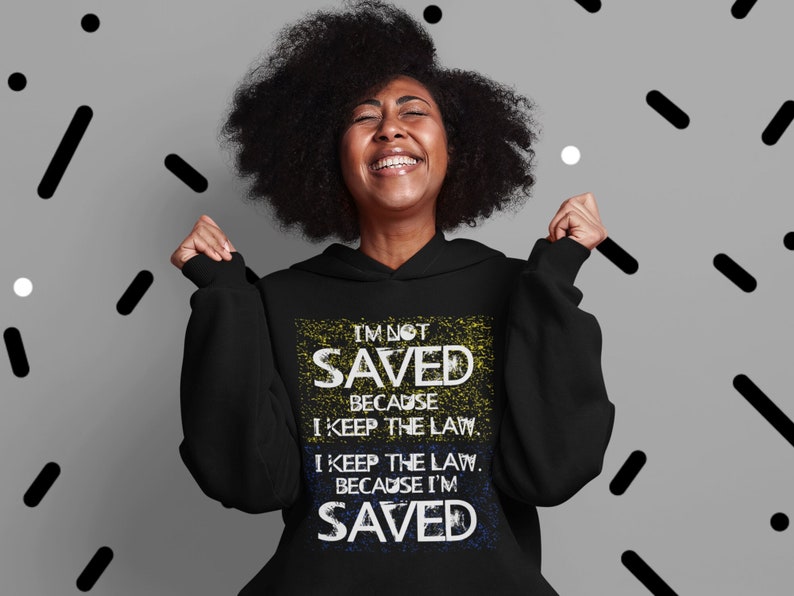 May include: Black hoodie with a white and yellow graphic print that reads "I'm not saved because I keep the law. I keep the law because I'm saved."