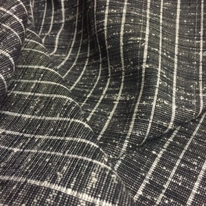 May include: Black and white striped fabric with a textured surface. The fabric is woven with thin white stripes on a black background.
