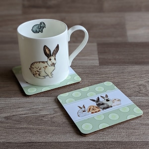 Peut inclure: Un ensemble de deux dessous-de-verre en céramique avec un motif de pois verts et blancs, une bande blanche et des illustrations de lapins. Un dessous-de-verre présente un seul lapin, tandis que l'autre présente quatre lapins.