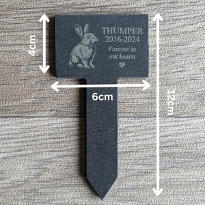 Puede incluir: Un marcador de jard&iacute;n de pizarra negra con una silueta de conejo blanco y el texto "THUMPER 2016-2024 Forever in our hearts". El marcador mide 10 cm de alto y 30 cm de ancho.