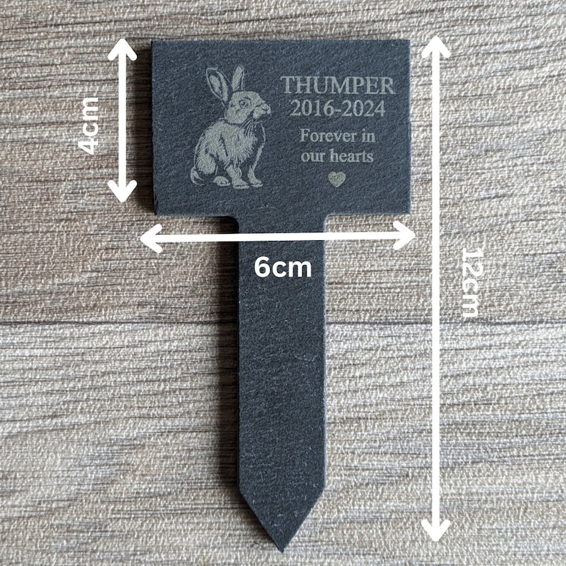 Puede incluir: Un marcador de jard&iacute;n de pizarra negra con una silueta de conejo blanco y el texto "THUMPER 2016-2024 Forever in our hearts". El marcador mide 10 cm de alto y 30 cm de ancho.